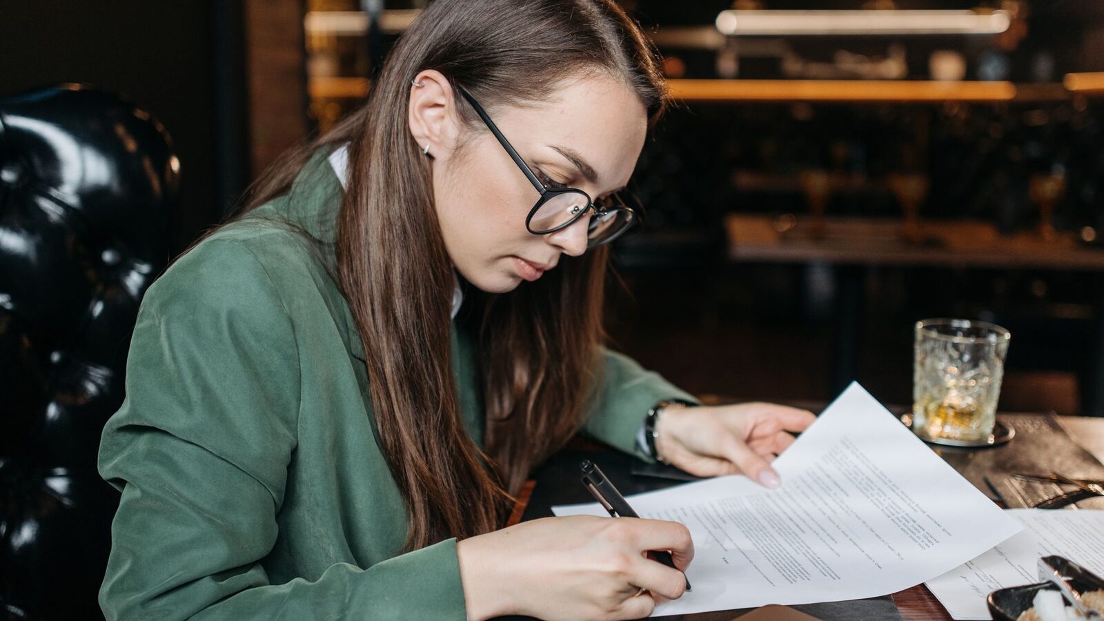 Personne remplissant un dossier de remboursement de lunette, lunettes sur la table