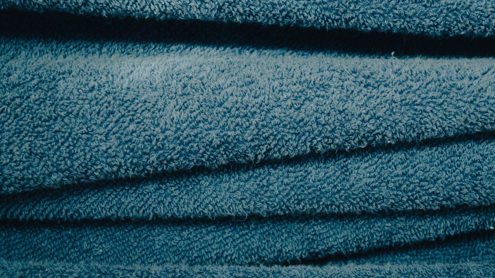 Serviettes de toilette bleues empilées, texture éponge visible de près