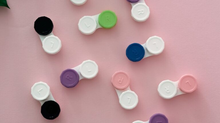 Boîtiers de lentilles de couleur disposés à plat sur un fond rose