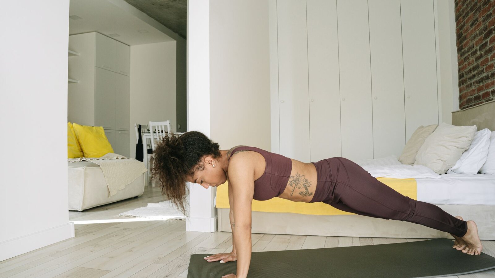 Femme en tenue souple qui étire sa jambe au pied du lit, le matin