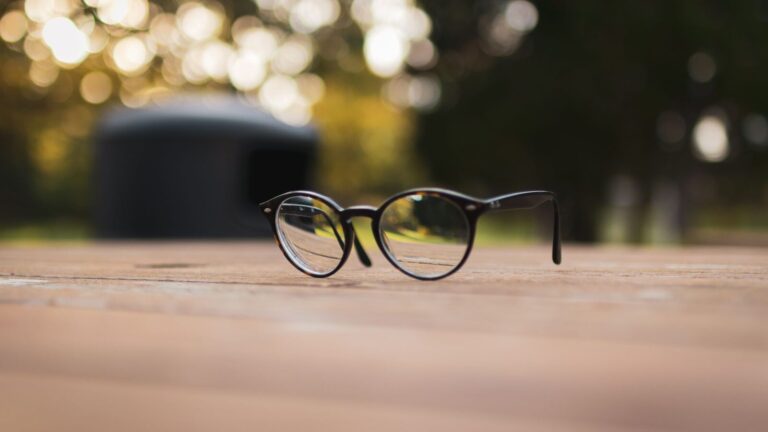 Paire de lunettes de vue posée sur une table en bois éclairée par le soleil