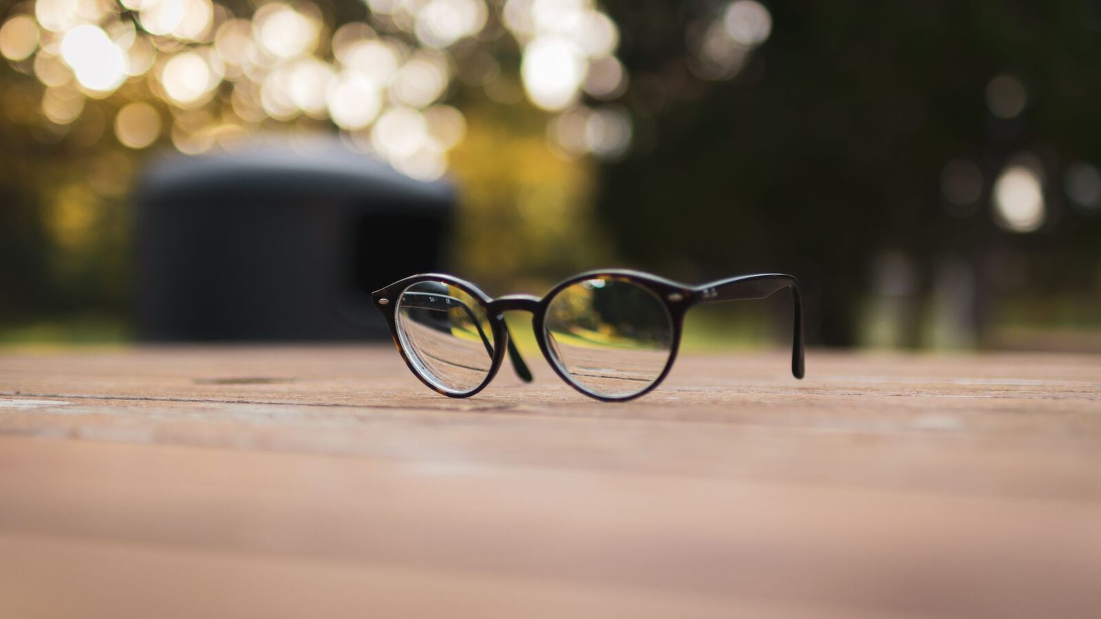 Paire de lunettes de vue posée sur une table en bois éclairée par le soleil